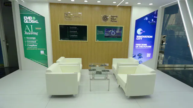 Inside the EMB Global stand at ADNEC: timber slat wall, two screens and white lounge seating