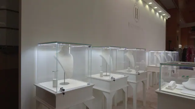 Glass-topped jewellery showcase with white display forms, lit from inside