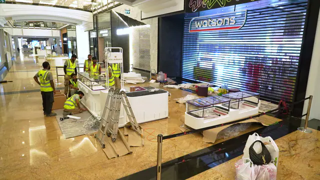 Lines & Designs installers assembling kiosk counters on a mall concourse at night
