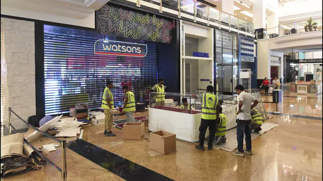 Installers in hi-vis vests fitting display units on a mall concourse at night